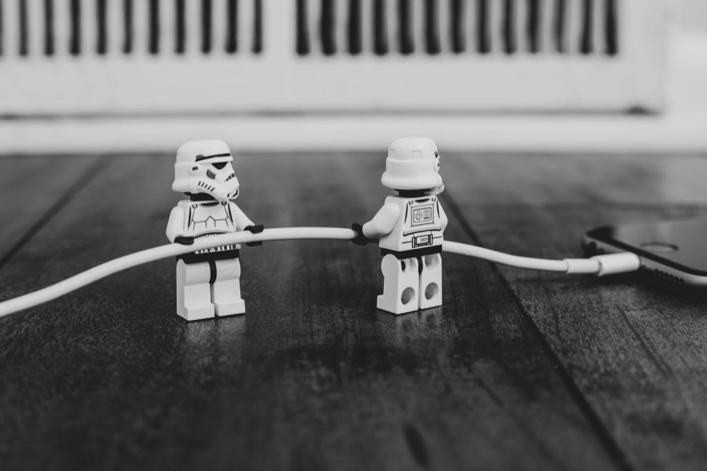 Two Lego Star Wars Storm Troopers holding a white cable into a mobile phone